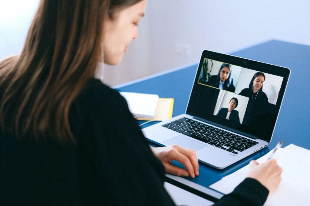 Woman looking down at a laptop screen with video footage of her colleagues